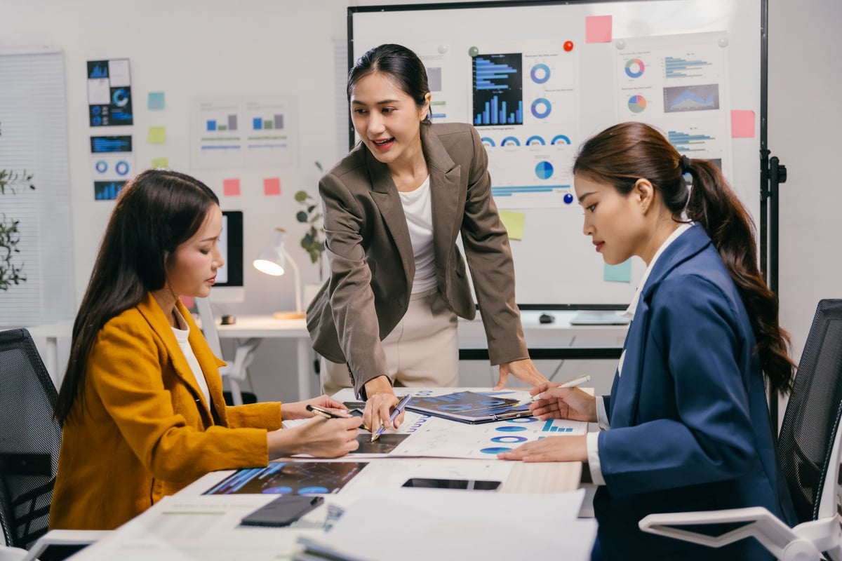 Three professionals collaborating over charts and data in a modern office